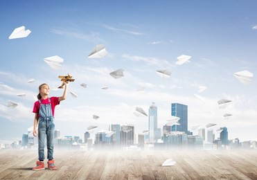 cute kid girl stand on wooden floor and paper planes flying around
