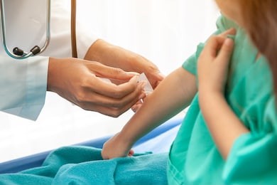 doctor or nurse or pediatrician in uniform talking or examining illness  after giving an injection or saline against  little girl at hospital,together. vaccination healthcare  children concept