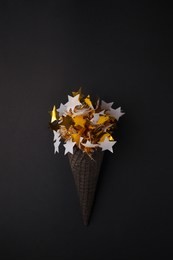 black ice cream cone with white gold star garland on black background, monochrome party minimal closeup