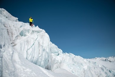 a freerider skier in complete outfit stands on a glacier in the north caucasus. skier preparing before jumping from the glacier