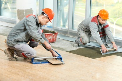 two industrial tiler builder worker installing floor tile at repair renovation work