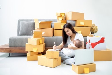 asia mother working with laptop while her holding a daughter at the home. shopping online and single mom concept.
