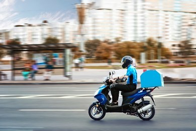 delivery boy of takeaway on scooter with trunk case box driving fast in rush. courier delivering food by scooter to avoid traffic jams. 