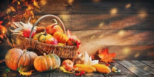 thanksgiving pumpkins with fruits and falling leaves on rustic wooden table