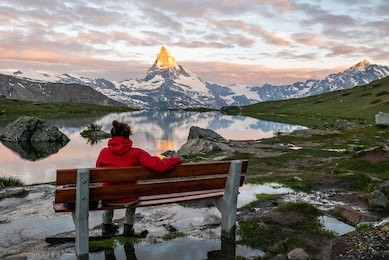 morning shot of the golden matterhorn (monte cervino, mont cervin) pyramid and  blue stellisee lake. female tourist enjoying view of early morning matterhorn mountain is valais alps, switzerland.