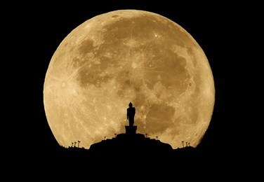 buddha statue silhouette on full moon background.