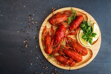 boiled cooked crayfish crawfish ready to eat on wooden plate on black background. copy space.