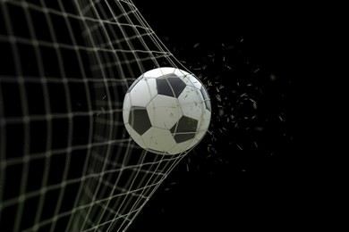 soccer ball in goal with grass leaves that raises effect on black background, concept of competition and leisure game equipment