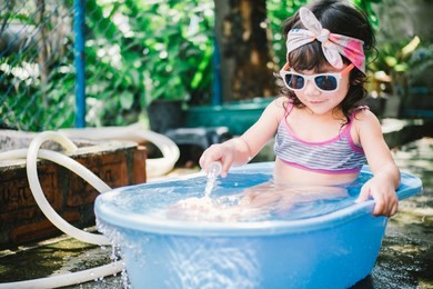 adorable little girl having fun wearing sunglasses play in the blue bathtub.