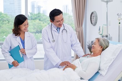 vietnamese doctor and nurse visiting senior woman after surgery