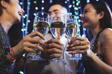 group of young people clinking cocktails glasses at night party