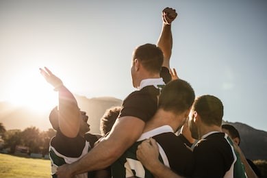 rugby players lifting the teammate after winning the game. rugby team celebrating the victory.