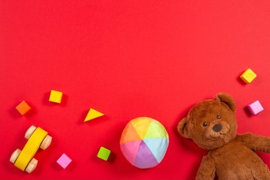 baby kids toys background. teddy bear, wooden car, colorful bricks on red background