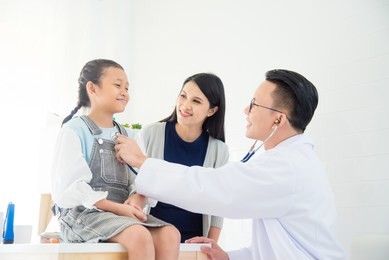 asian doctor examining a girl by stethoscope ,mother standing beside her daughter at hospital