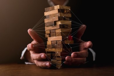business man try to build wood block on wooden table and black background business organization startup concept