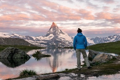 morning shot of the golden matterhorn (monte cervino, mont cervin) pyramid and  blue stellisee lake. female tourist enjoying view of early morning matterhorn mountain is valais alps, switzerland.