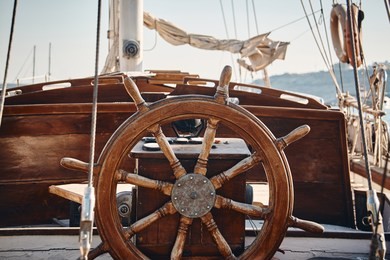 closeup of a vintage hand wheel on a wooden sailing yacht. yachting, helm of old wooden sailboat in port of sailing, rope, steering wheel, details of yacht.