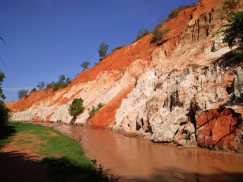 
beautiful natural colors at the fairy stream.
the blue sky, a canyon of red-rock cliffs and its stream, a white color at the lower part, and green grasses and trees at partly.