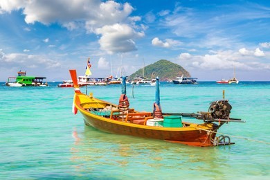 traditional long tail boat on coral (ko he) island near phuket island, thailand in a summer day