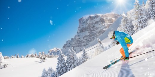 skier skiing downhill during sunny day in high mountains