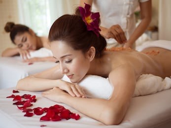 young asian woman receiving salt massage in spa salon