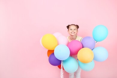 cute young girl with colored balloons on pink background