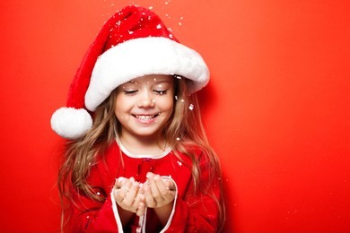 happy smiling funny girl in christmas cap under the snow on the red background. merry christmas. sale. black friday.