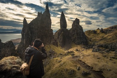 asian tourist take a photo on beautiful landscape scenery at the the old man of storr, isle of skye, scotland at twilight hours