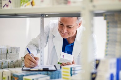 male pharmacist checking medicines inventory at hospital pharmacy. pharmacist in drugstore or pharmacy taking notes. portrait of health care doctor in pharmacy writing on clipboard