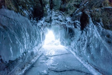 winter landscape, frozen ice cave with bright sunlight from way out at frozen lake baikal in siberia, russia