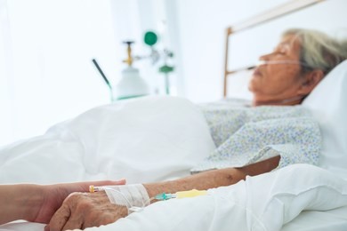 medical doctor holing senior patient's hands and comforting her, hand of man touching senior woman in clinic, care for the elderly concept