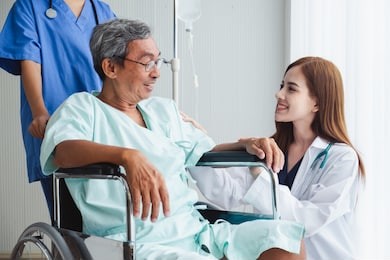 asian doctor woman and nurse encourage disabled old man patient sitting on wheelchair at hospital, asian medical concept