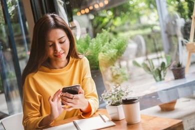 young asian beautiful woman using smart phone for business, online shopping, transfer money, financial, internet banking. in coffee shop cafe over blurred background.