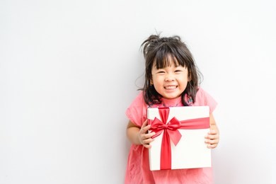 little asian girl smile and excited and holding red gift box on white background.child holding gift box in christmas and new year concept.