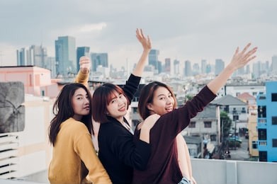 happy group of asia girl friends enjoy and arm up relax pose at roof top party at evening sunset,holiday celebration festive,teenage lifestyle,freedom and fun