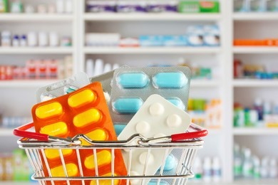 medicine pill tablet in shopping basket with pharmacy drugstore shelves blurred background