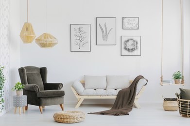 brown armchair, wooden sofa and blanket in a bright living room interior. real photo