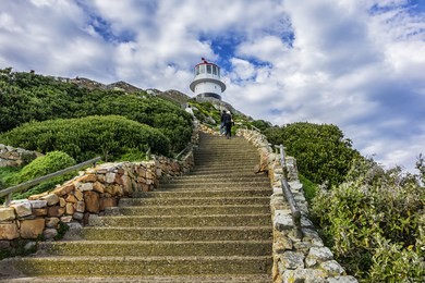 a lighthouse sits on top of cliffs of cape point in the cape of good hope nature reserve on southern tip of the cape peninsula in south africa. the atlantic and indian oceans converge at cape point.