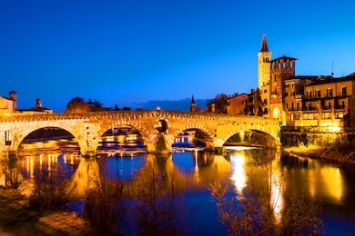 verona, italy. old town verona, italy. illuminated bridge with other landmarks. colorful historical buildings at night