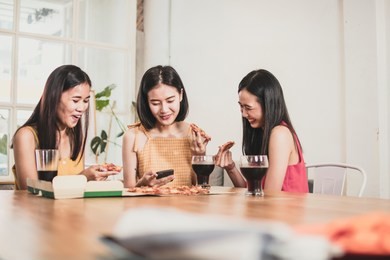 asian teenagers eating pizza and soda at home, funny food party concept 