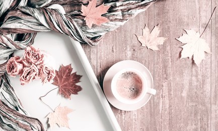 autumn composition. cup of coffee, autumn dry leaves and roses, cones, scarf on  light pastel beige background.  autumn, fall, concept. flat lay, top view, copy space
