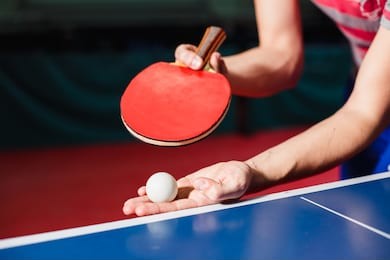 a young man is playing ping pong. he holds a ball and a racket in his hands