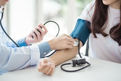 doctor using sphygmomanometer with stethoscope checking blood pressure to a patient in the hospital.