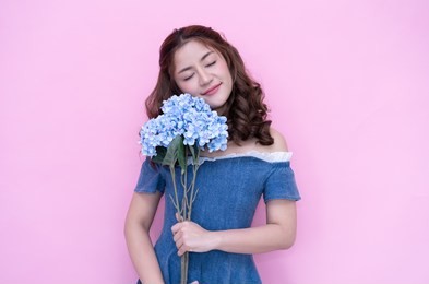 young asian woman in blue dress with bouquet on pink background.international women's day holiday concept