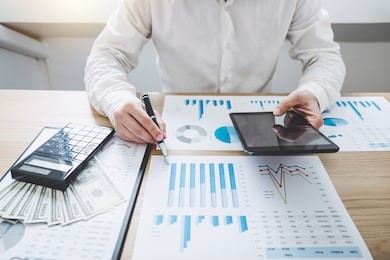 finances saving banking concept, man accountant calculations income on digital tablet and analyzing financial graph data with calculator.