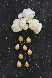 concept with popcorn and corn - popcorn corn rains from a poped corn - cloud with rain as popcorn and corn in front of a black background and sugar grains around