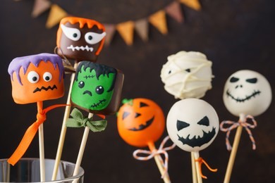set of halloween treats on stick: frankenstein, ghost, pumpkin; mummy on dark background.