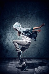 urban hip hop dancer with grunge concrete wall background texture jumping and dancing with hoodie