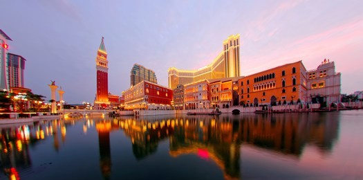 scenic view of the grand exterior of  macao in evening twilight, a luxury hotel & casino resort in macau, china, with beautiful reflections of the majestic buildings at dusk in the water