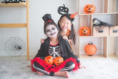 little asian girls sitting and smile in room decorated for halloween day